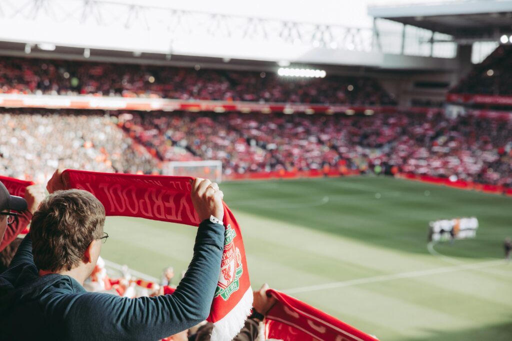 Kibic Liverpoolu trzymający szalik klubu na stadionie wśród publiczności