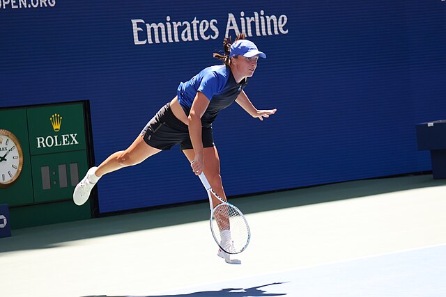 Iga Świątek opada na ziemie po oddanym serwisie