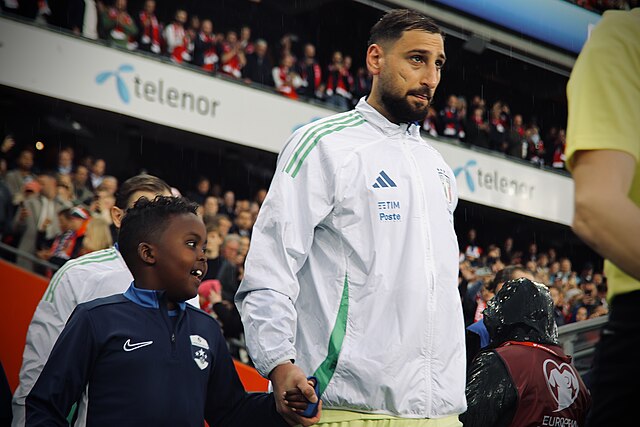 Gianluigi Donnaruma wychodzi na boisko, trzymając dłoń dziecka