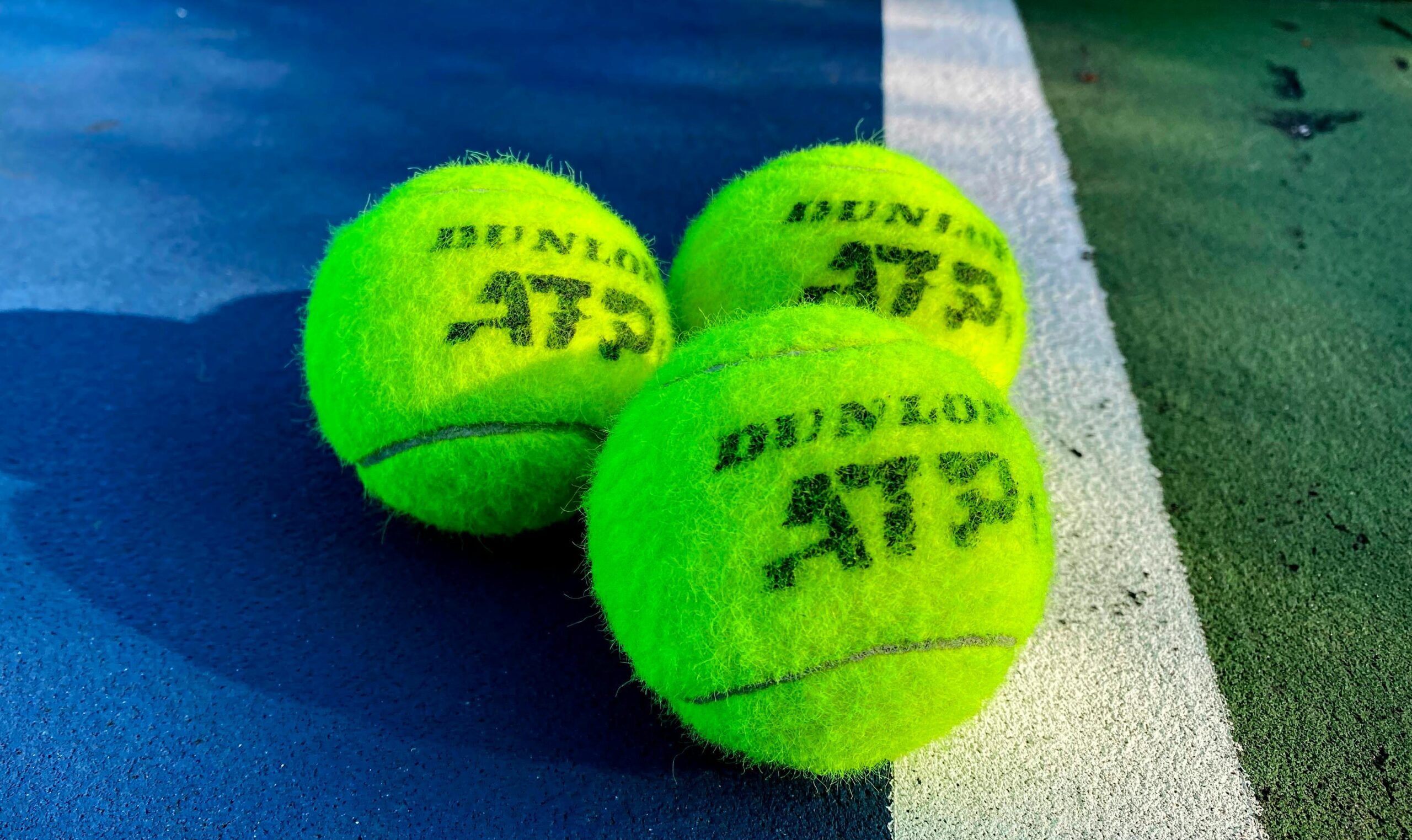 Zbliżenie na trzy piłki tenisowe ustawione przy linii