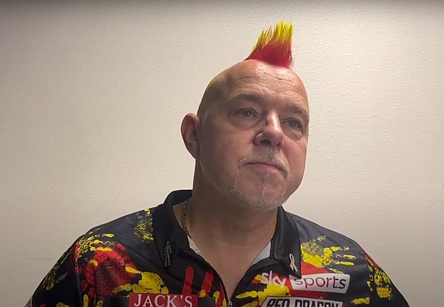 Peter Wright na tle białej ściany