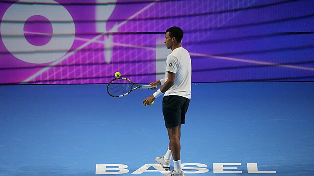 Felix Auger-Aliassime trzymający rakietę, na której umieszczona jest piłka tenisowa