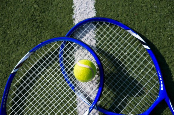 Dwie skrzyżowane rakiety z piłką postawioną na górze