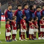 Drużyna FC Barcelony stojąca w rządku wraz towarzyszącymi dziećmi