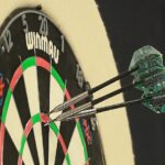 Trzy lotki wbite w tarczę darterską