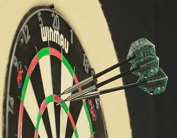 Trzy lotki wbite w tarczę darterską