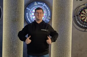 Sebastian Białecki stojący na tle tarczy z kciukami w górę