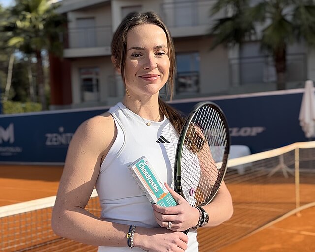 Elina Svitolina stojąca na tle siatki z rakietą