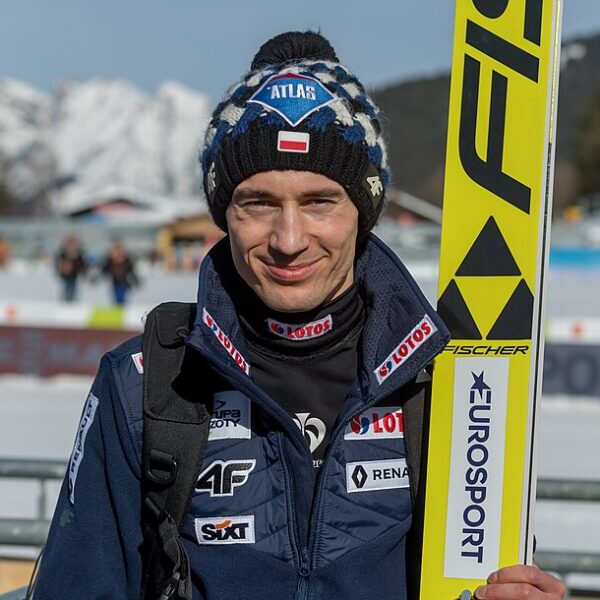 Uśmiechnięty Kamil Stoch z nartami w ręce