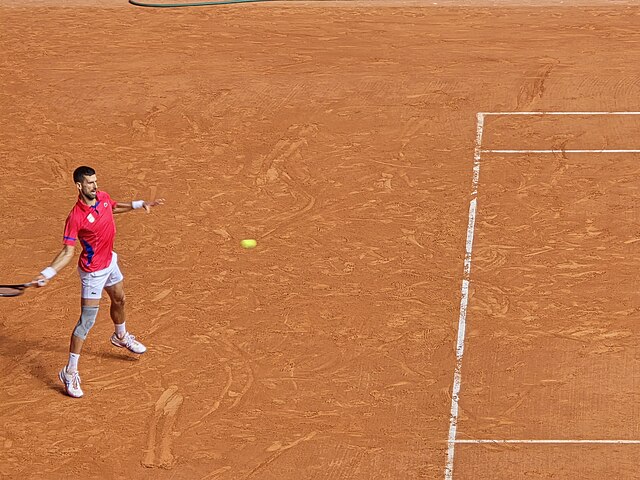 Novak Djoković zagrywający forehand dwa metry od linii końcowej
