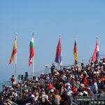 Flagi narodowości na tle kibiców i morza