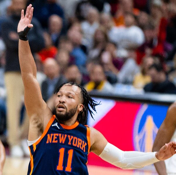 Jalen Brunson z wystawioną rękę w górze próbuje powstrzymać obrońców