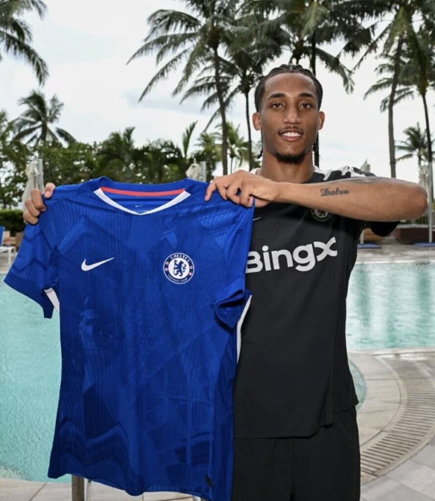 Joao Pedro trzyma koszulkę Chelsea na tle palm