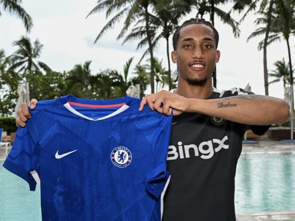 Joao Pedro trzyma koszulkę Chelsea na tle palm