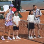 Iga Świątek i Marta Kostyuk ustawione przy siatce z dziećmi