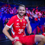 Bartłomiej Bołądź siedzący na barierkach z zaciśniętą pięścią